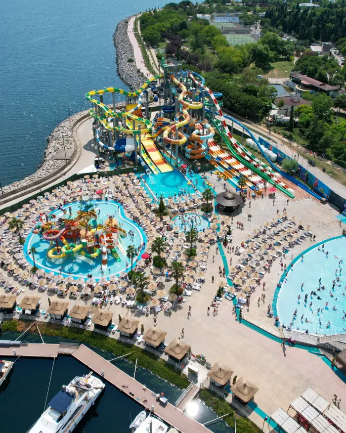 Marina Aquapark'ın havadan görünümü: solda deniz, ortada kaydırak kuleleri ve çocuk havuzu, sağda dalga havuzu, altta Viaport Marina iskelesi